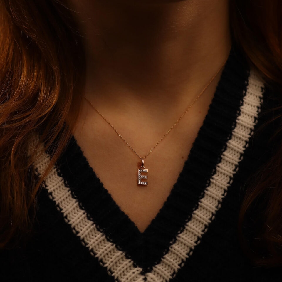 złota zawieszka litera "E" na szyi