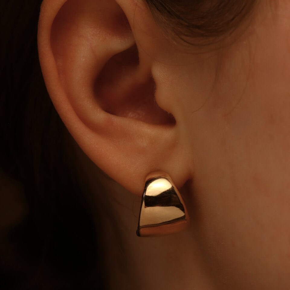 Złote kolczyki "Fale" w uchu